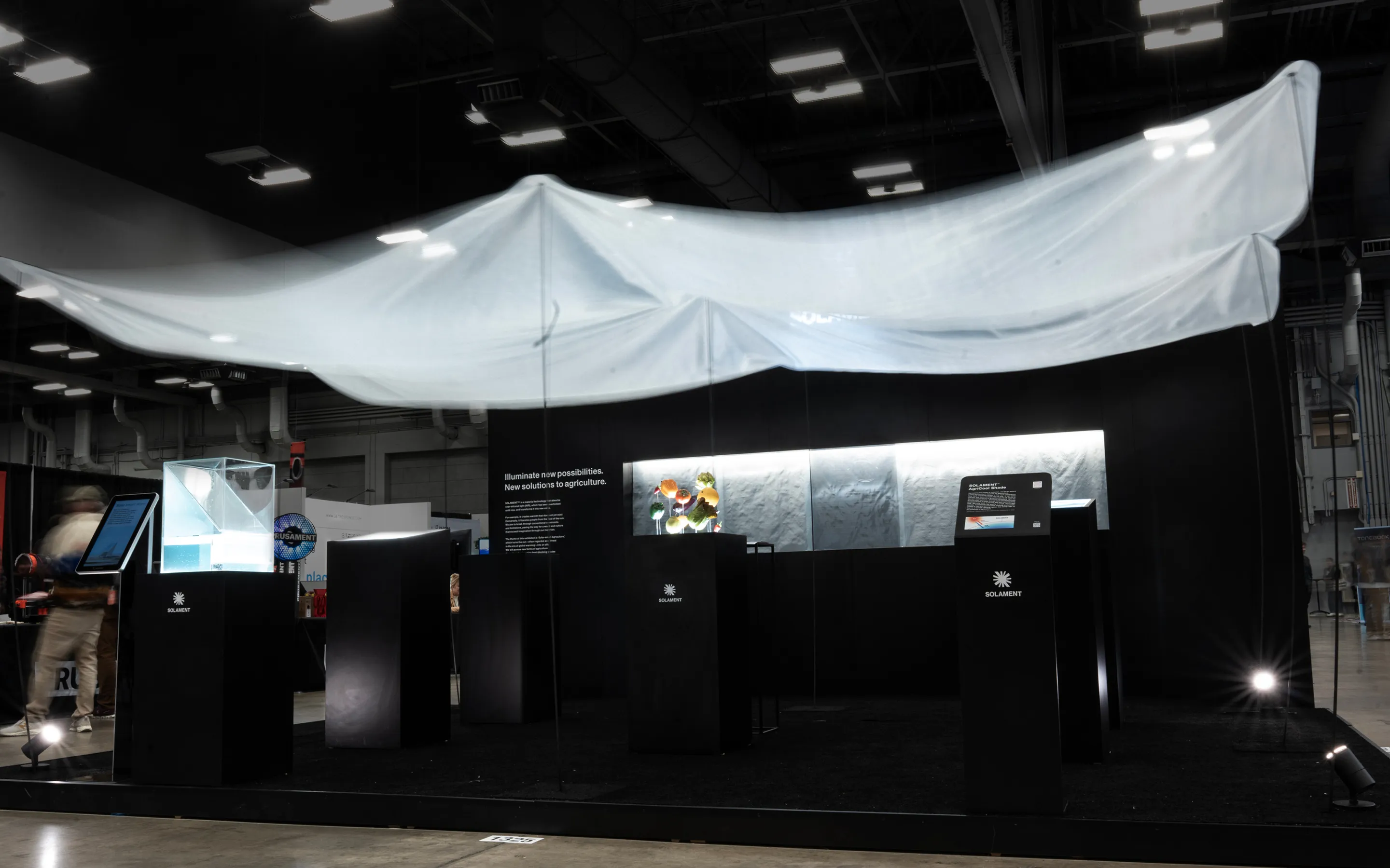 SXSW2025の様子。黒を基調とした農業向けSOLAMENT®の展示ブースで、頭上に透け感のある巨大な布（農業用シェード）が張られ、下には野菜などが展示されているビジュアル