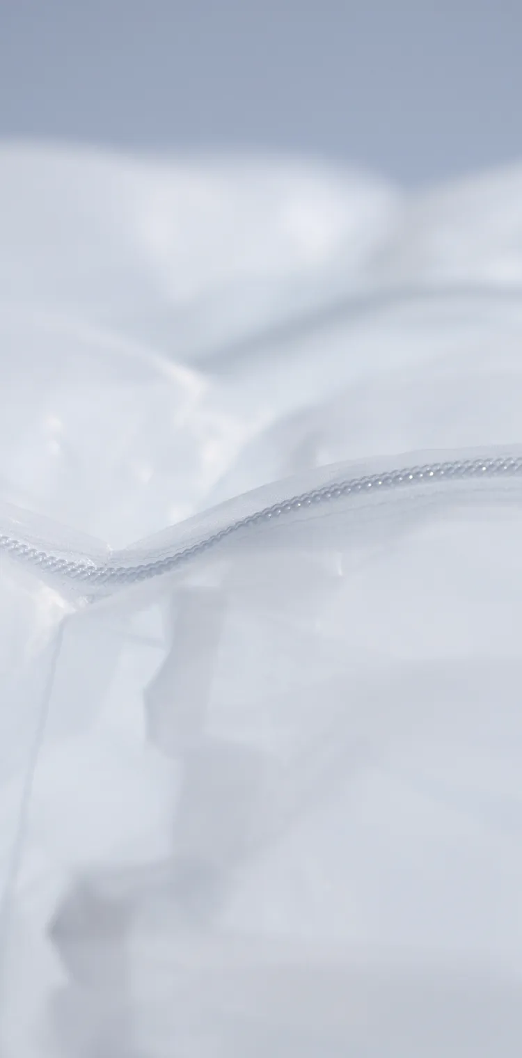 SOLAMENT®（ソラメント）を用いた新しいファッションの形を体現する素材の接写。光を柔らかく反射する白い半透明の素材と、シームレスに閉じたジッパーが、遮熱機能と洗練されたデザイン性を象徴するメインビジュアル。