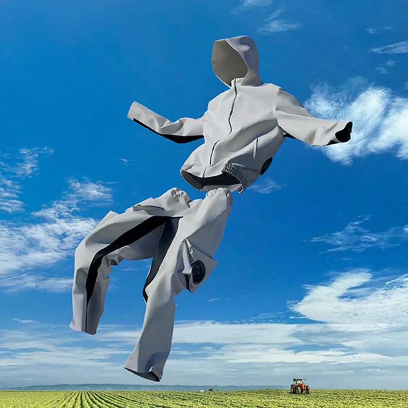 鮮やかな青空を背景に、ファンが組み込まれた白い農作業用ウェア上下セット（HOPE WEAR for Farm Type A）が空中に浮いているイメージビジュアル。
