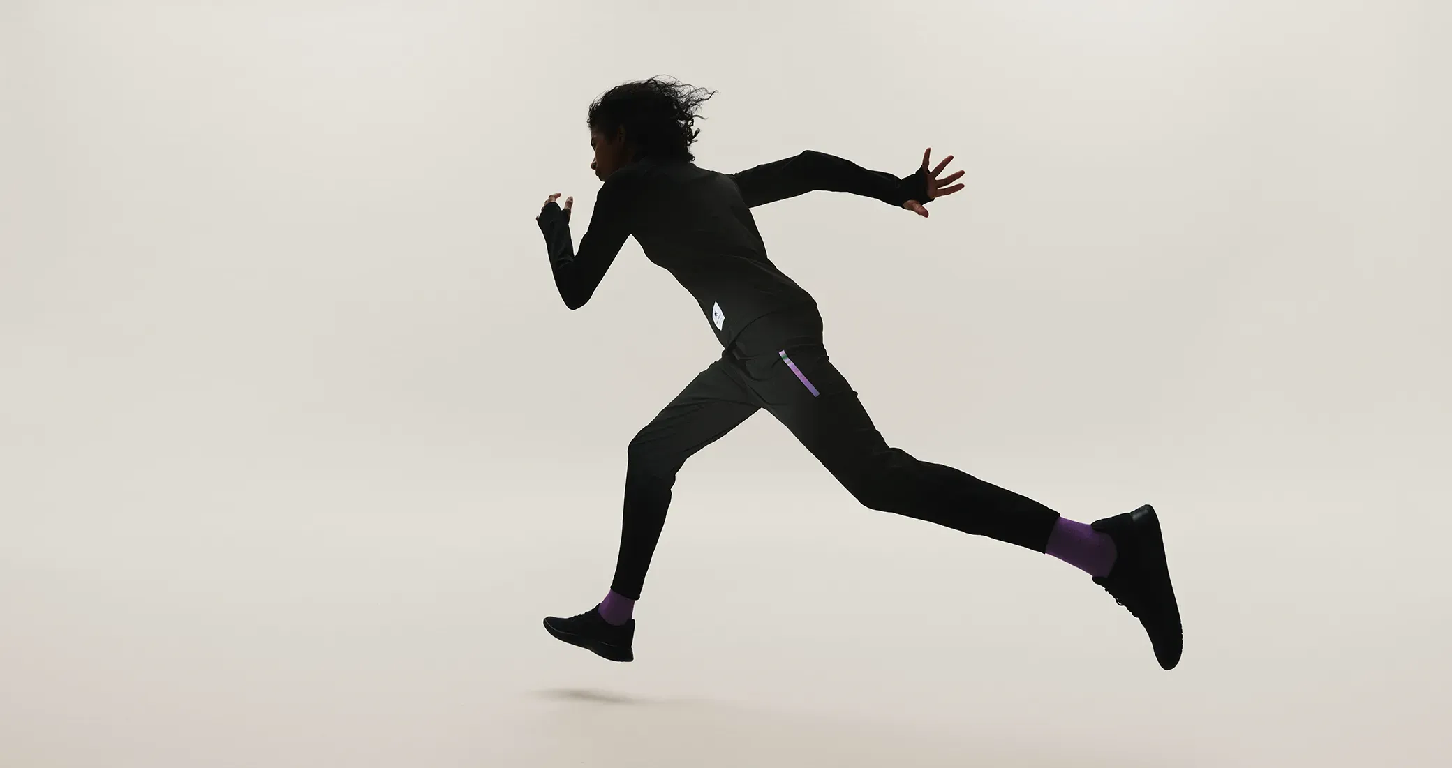パープルのアクセントが光るシルエット。SOLAR-PERFORMANCE WEARを着用し、寒冷環境での躍動的なランニングしている。